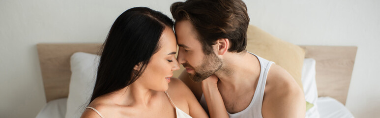 bearded man looking at brunette girlfriend in bedroom, banner