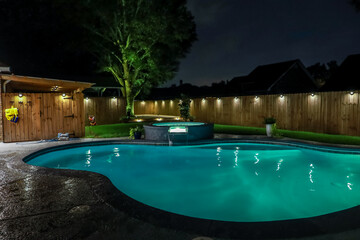 A backyard swimming pool and jacuzzi hot tob at night - Powered by Adobe