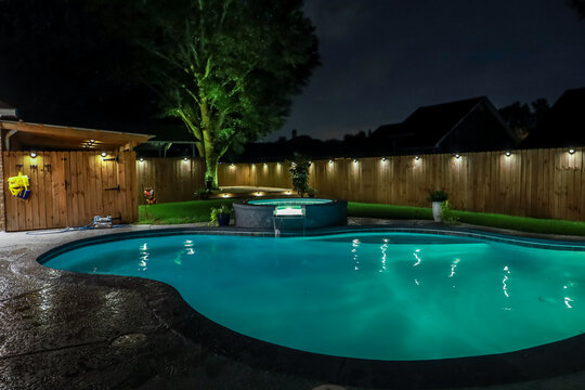 A backyard swimming pool and jacuzzi hot tob at night