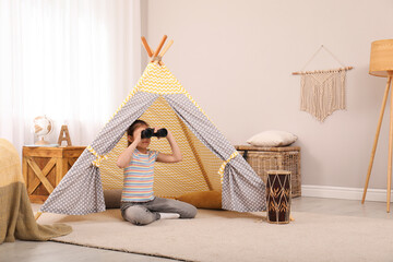 Cute little girl with binoculars in toy wigwam at home © New Africa