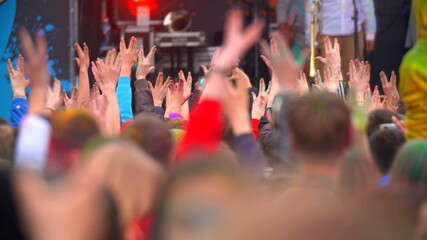 Crowd of happy people at concert dancing and waving hands
