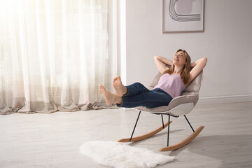 Beautiful young woman sitting in rocking chair at home