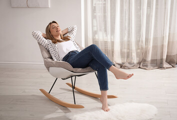 Beautiful young woman sitting in rocking chair at home - Powered by Adobe