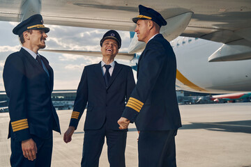 Three airline pilots enjoying each other company - obrazy, fototapety, plakaty