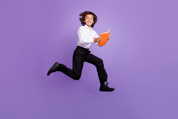 Fototapeta na wymiar Full body photo of cool small brunet boy run read book wear shirt trousers sneakers isolated on purple color background