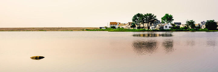 Obraz premium Tranquil seascape with a view of a zen-like rock and beach village on the sandbar peninsula