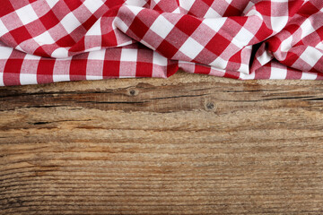 Checkered red and white table cloth on wooden background, copy space.