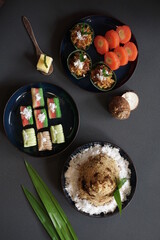 Traditional asian food cooked with cassava, coconut, banana, brown sugar which served with blue beauty plate on dark grey background