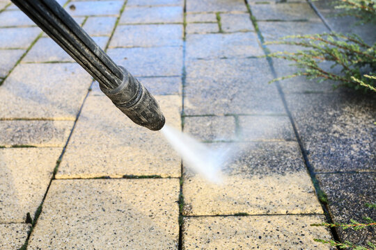 Cleaning dirty paving stones in the garden with a pressure washer.
