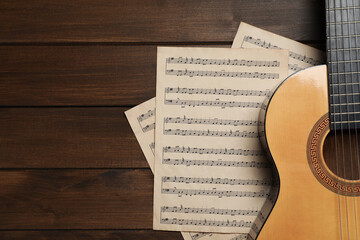 Composition with guitar and music notations on wooden table, flat lay. Space for text