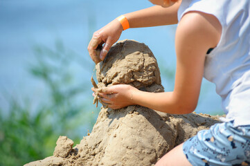 Little girl hands making a sand sculpture on a beach of a river