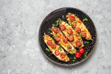 Baked eggplants with cherry tomato and cheese on a gray grunge background. Top view, flat lay, copy space.