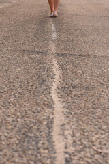 Unrecognizable girl walking in the middle of the street.