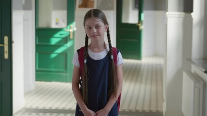 Portrait of smiling caucasian schoolgirl standing in school corridor wearing schoolbag. - Powered by Adobe