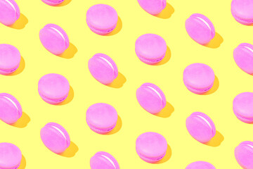Creative pattern made of pink macaroons on yellow background. Dessert and confectionary concept.