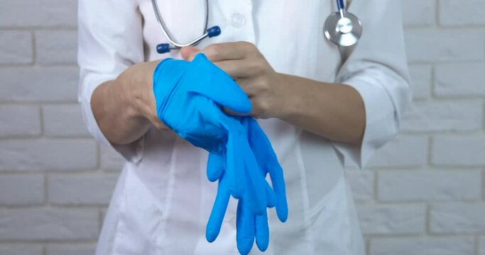 Put on medical gloves. A professional doctor puts on her medical gloves before examining the patient. A concept of self protection during epidemic.