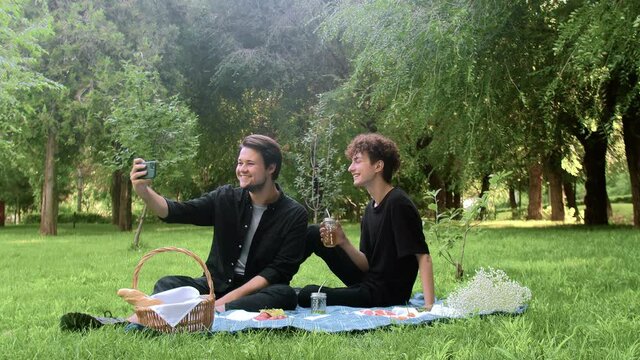 Two young guys are photographed on the phone in nature in the summer