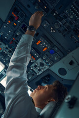 Male pilot turning the switch on the overhead panel