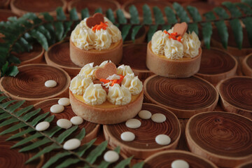 dessert, cheesecake with mango and passion fruit in the form of brownies with mousse on top. Decorated with cookies in the form of a heart. On a wooden table in a white plate