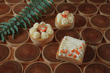 dessert, cheesecake with mango and passion fruit in the form of brownies with mousse on top. Decorated with cookies in the form of a heart. On a wooden table in a white plate