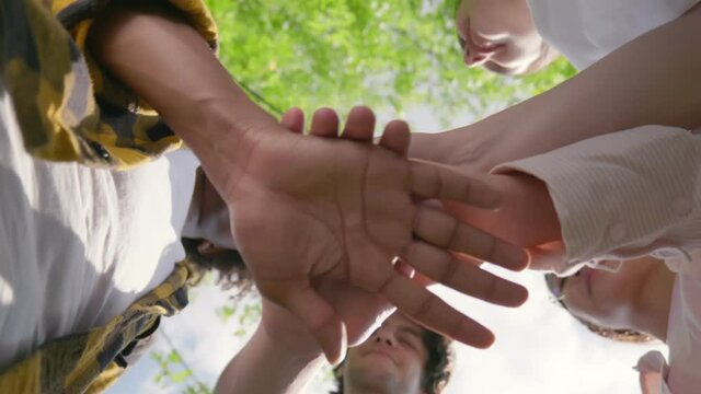 Close up bottom view of diverse people putting hands together.