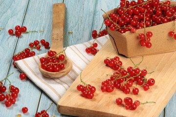 Red currant on blue wooden tablebackground. Cup and jar with fresh red currants (ribes rubrum).