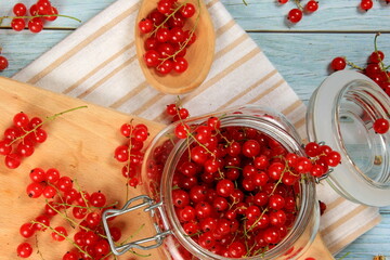 Red currant on blue wooden tablebackground. Cup and jar with fresh red currants (ribes rubrum).