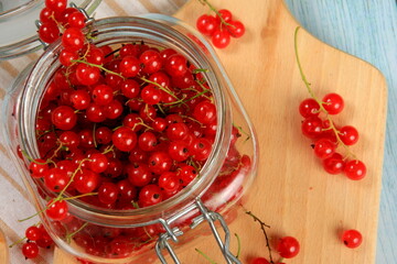 Red currant on blue wooden tablebackground. Cup and jar with fresh red currants (ribes rubrum).