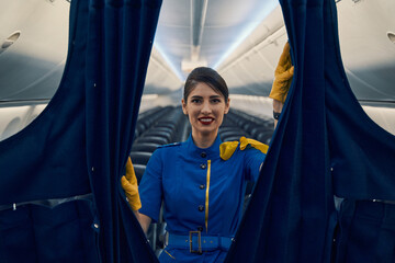 Air hostess closing the curtains in the business class area