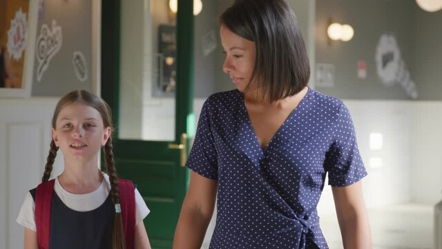 Slider shot of afro-american female teacher and preteen girl pupil walk in school corridor and talk