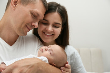 Happy family with their cute sleeping baby on grey background