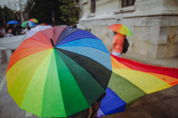 People hold rainbow umbrellas during a LGBTQ gay pride protest.