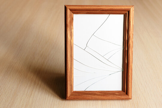 Cracked Glass. Wooden Frame For The Picture. Light Wood Surface.