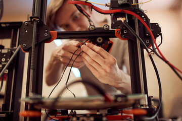 Young male technician fixing 3D printer