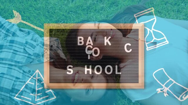 Back to school text on wooden slate against two caucasian female college students lying on the grass