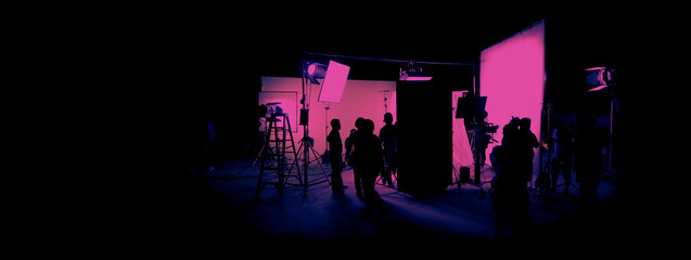 Silhouette images of film production. behind the scenes or b-roll of making video commercial movie. Film crew lightman and cameraman working together with film director in studio. Film industry. - obrazy, fototapety, plakaty