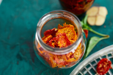 Homemade sun dried tomatoes with herbs, garlic in olive oil in a glass jar