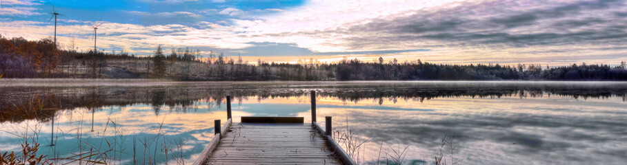HDR Panorama over a Swedish lake by sunset/sunrise with a jetty and two wind-power generators