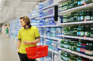 Young man shopping in supermarket, reading product information