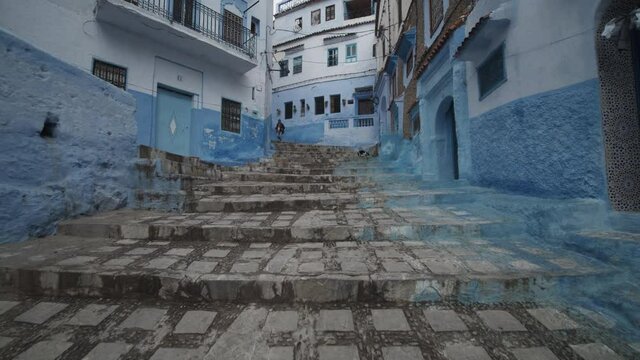 Low flight above stairs in blue city of Chefchaouen. Old traditional buildings with blue painted facades. Morocco, Africa