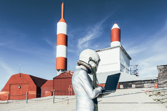 Cosmonaut using laptop near base