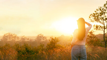 Fototapeta premium Young woman standing and looking to sunrise at the top of mountains.