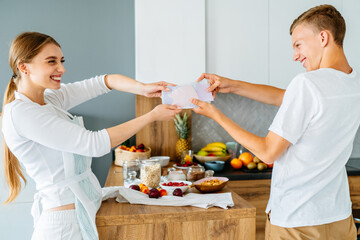 Teenage brother and her adult sister, young in 20s, fighting for sweet food at cozy home kitchen interior.