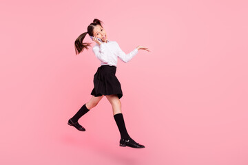 Full length photo of little brunette tails girl jump up wear uniform formalwear long socks talk jump isolated on pink color background
