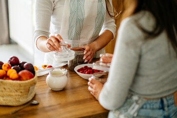 Different ingredients for cooking cereal breakfast on the table. Close up of two women hands cooking together at kitchen.