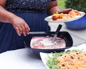Black woman serves herself at an outdoor buffet