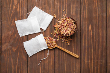 Tea bags and bowl with dry leaves on wooden  background