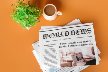 Newspapers with cup of coffee and houseplant on color background