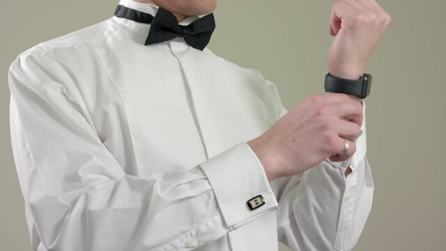 Man buttoning a cufflink on his white shirt sleeve. Man in bow tie dressing, slow motiom