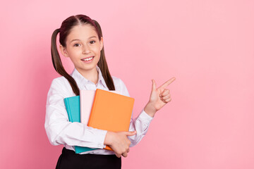 Fototapeta premium Photo of cute happy positive little girl point finger empty space hold notebook isolated on pink color background